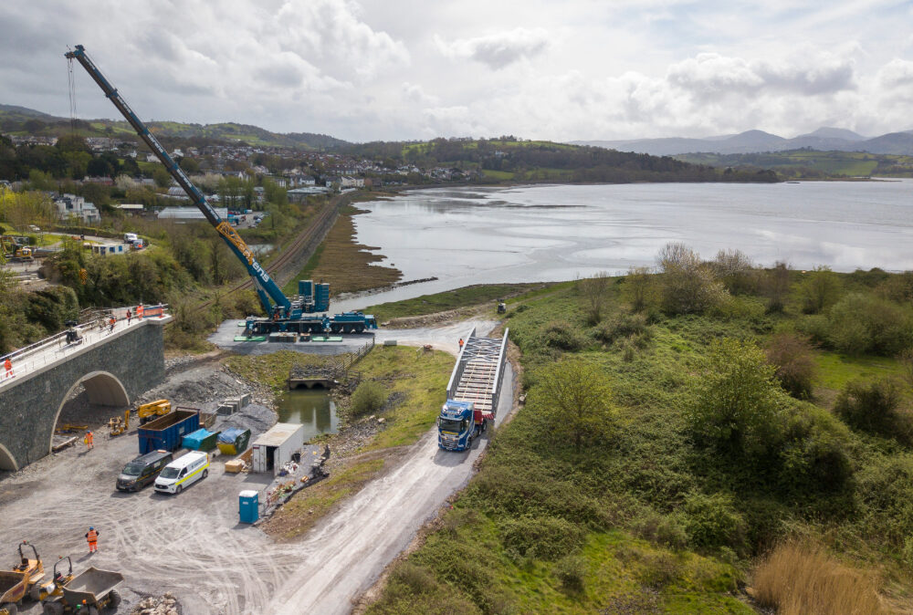 High-angle drone view of a Beaver Bridges project, showcasing heavy equipment and site logistics for a river crossing installation.